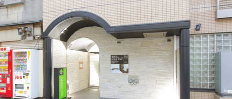 A building entrance with a tiled wall, a vending machine, and a signboard.