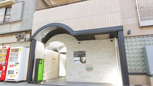 A building entrance with a tiled wall, a vending machine, and a Flexstax Inn sign. - Flexstay Inn Kawasaki-Kaizuka (Kawasaki)