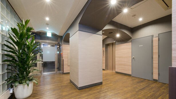 A modern hallway with wooden flooring, a potted plant, and private rooms with doors. - Flexstay Inn Kawasaki-Kaizuka (Kawasaki)