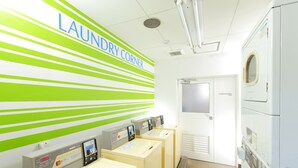 A laundry facility with four washing machines, a wall with green and white stripes, and a door labeled "Garbage Bins". - Flexstay Inn Kawasaki-Kaizuka (Kawasaki)