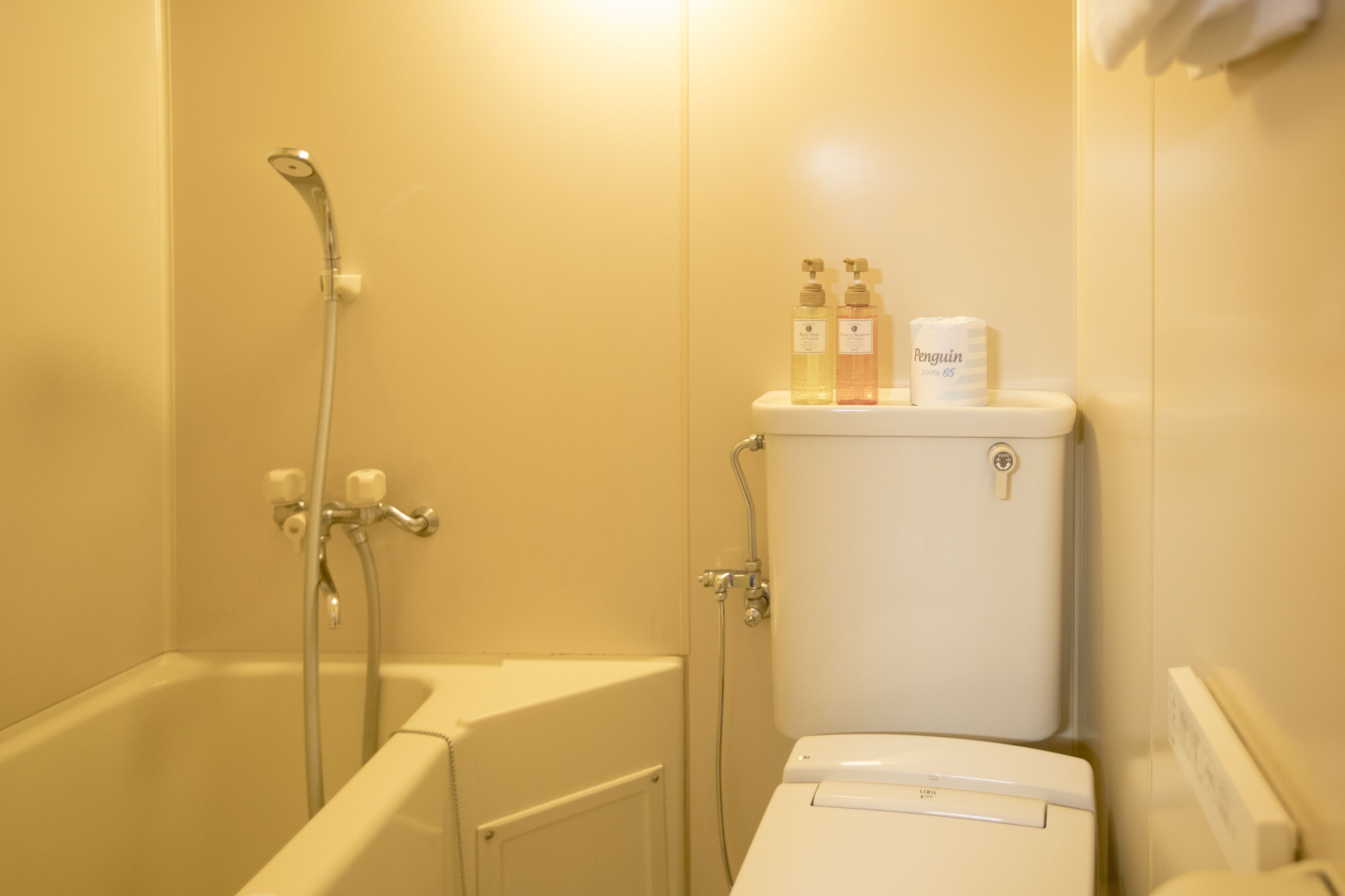 A bathroom with a bathtub, toilet, and shower. There are two bottles of liquid soap on the toilet tank.