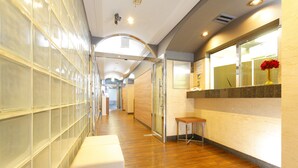 A hallway with a bench, a glass partition, and a wooden floor. - Flexstay Inn Kawasaki-Kaizuka (Kawasaki)