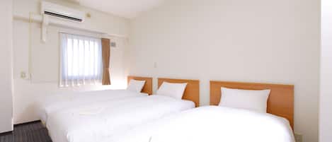 A hotel room with two single beds, a large window with curtains, an air conditioning unit, and a carpeted floor.