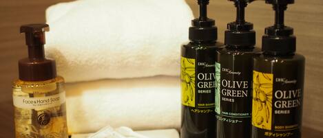Toiletries including face and hand soap, hair shampoo, and body shampoo, along with a toothbrush and a towel.