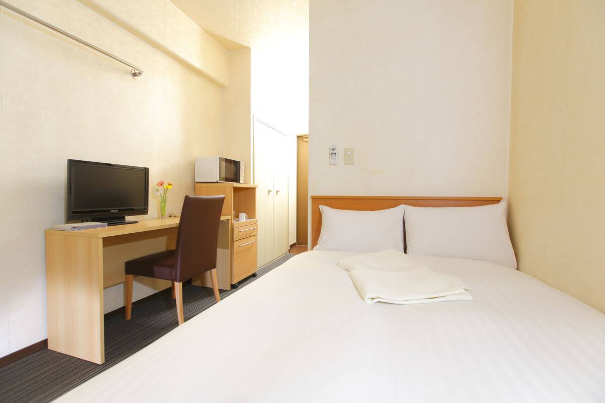 Une chambre d’hôtel comprenant un lit, un bureau avec un ordinateur, une chaise et un téléviseur.