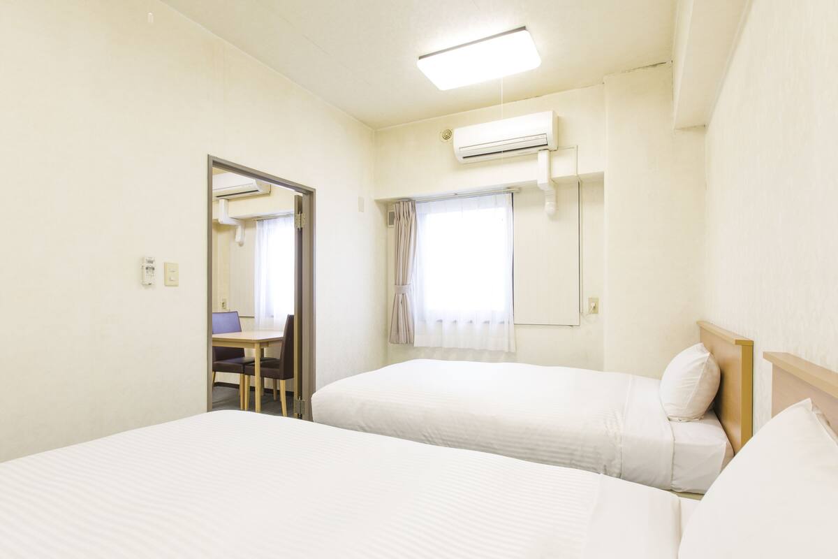 Une chambre d’hôtel avec deux lits, un bureau et une chaise.
