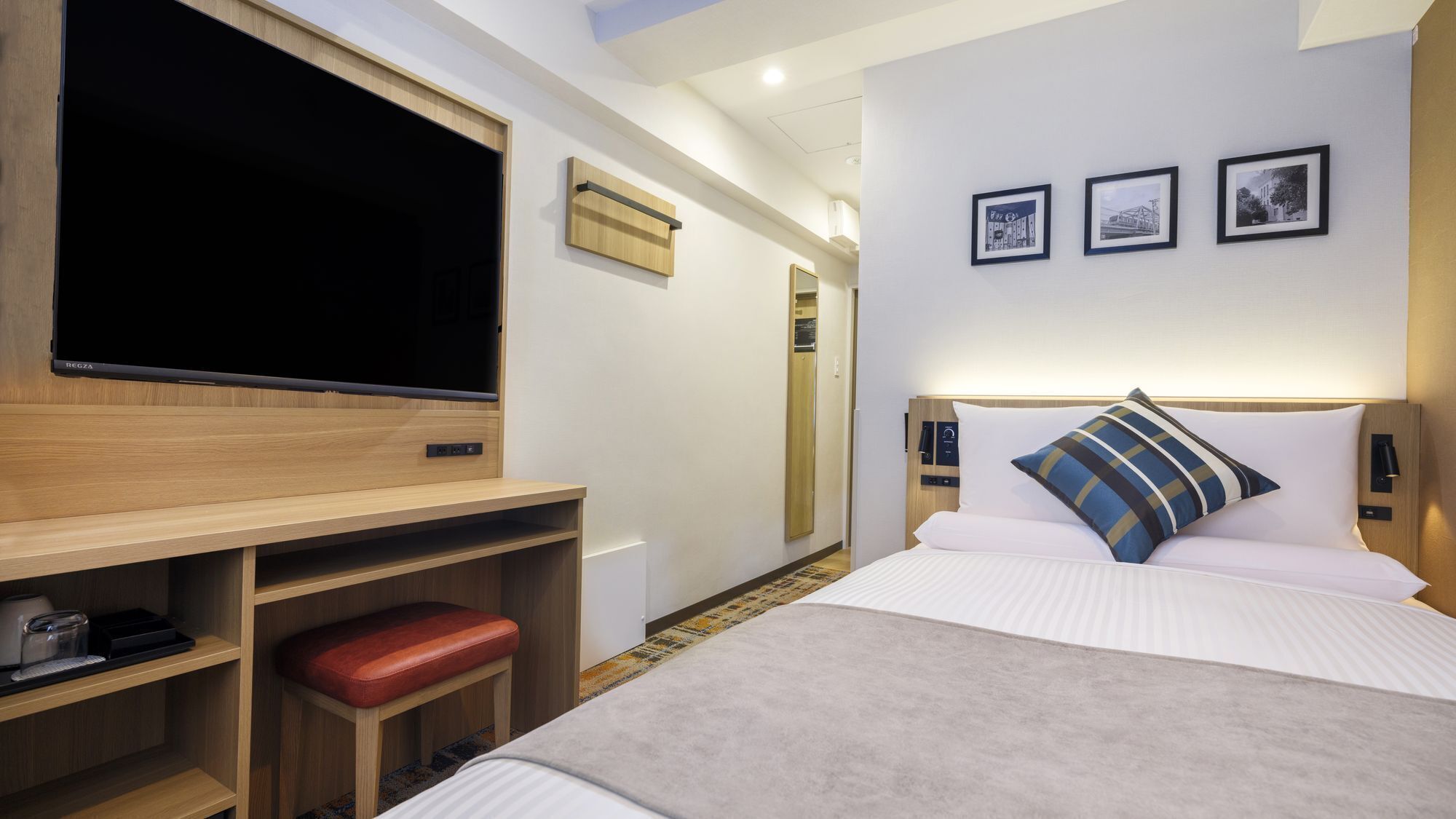 Una habitació d'hotel amb un llit, un escriptori amb una cadira, una televisió i un armari.