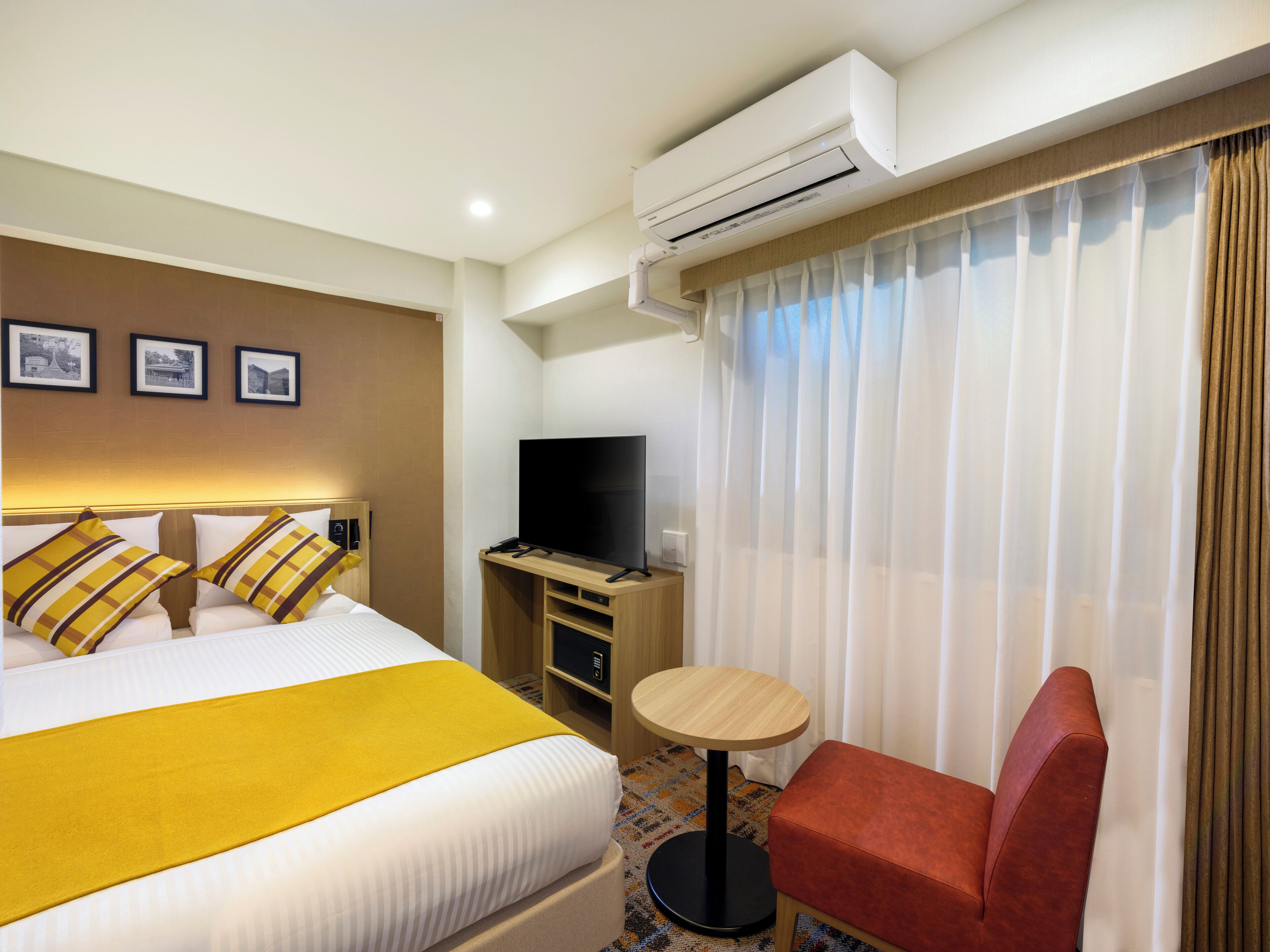 A hotel room with a bed, a television, a small table, and a chair.