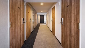 A hallway with wooden doors numbered 404 and 407, leading to a room. - Flexstay Inn Sakuragicho (Yokohama)