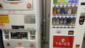 A vending machine with multiple beverage options and a red sign indicating a specific product. - Flexstay Inn Sakuragicho (Yokohama)