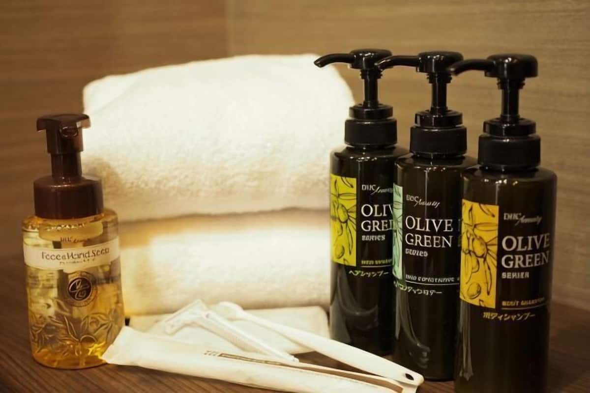 Une salle de bain avec une serviette blanche, un flacon de crème pour le visage et trois flacons de lotion pour le corps de couleur vert olive.
