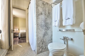 A bathroom with a toilet, a marble wall, and a shower curtain. - Centralia Square Grand Ballroom and Vintage Hotel (We are one of the only hotels located in downtown Centralia)  (Centralia)