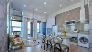 A modern kitchen with a built-in oven, a washing machine, and a dining area with a green sofa and chairs. - Sokcho Esher House Pension (Sokcho)