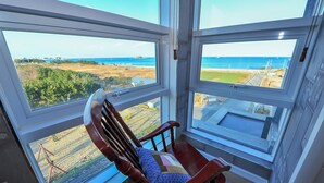 A corner room with a view of the ocean and a chair with a cushion. - Sokcho Esher House Pension (Sokcho)