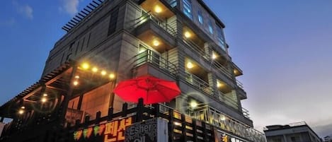 A multi-story building with illuminated signs and a red umbrella.