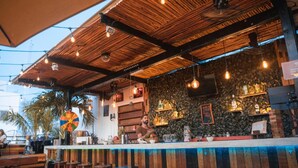 A bar area with a wooden ceiling, stone wall, and bar stools. - Che Playa Hostel & Bar (Playa del Carmen)