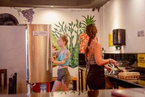 A kitchen area with a stainless steel refrigerator, a counter with food items, and a wall with a geometric mural.