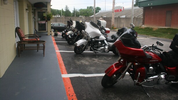 Varias motocicletas estacionadas frente a un edificio con un letrero de 'VACANCY'.