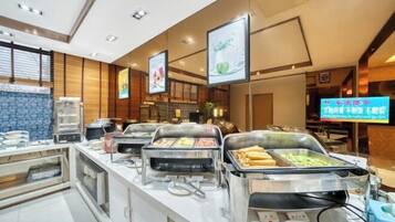 A buffet setup with multiple food stations, a television screen, and a modern interior design.