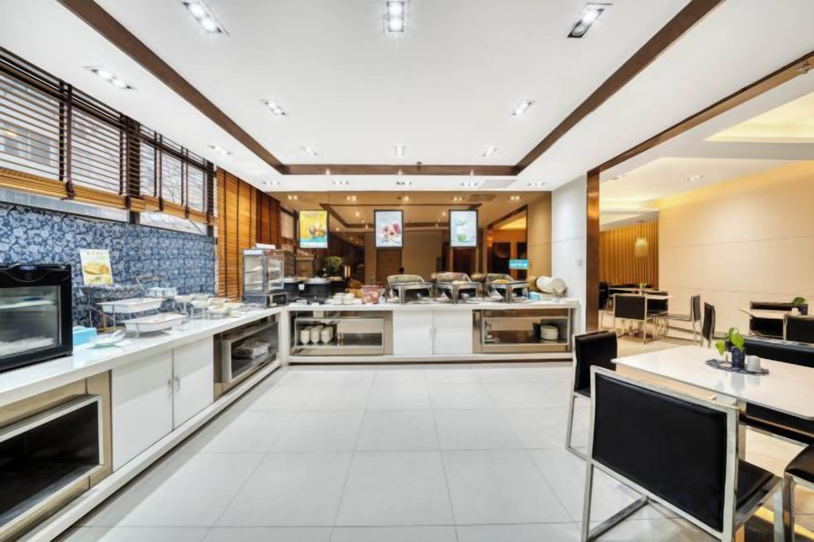 A modern hotel lobby with a reception desk, seating area, and a dining space.