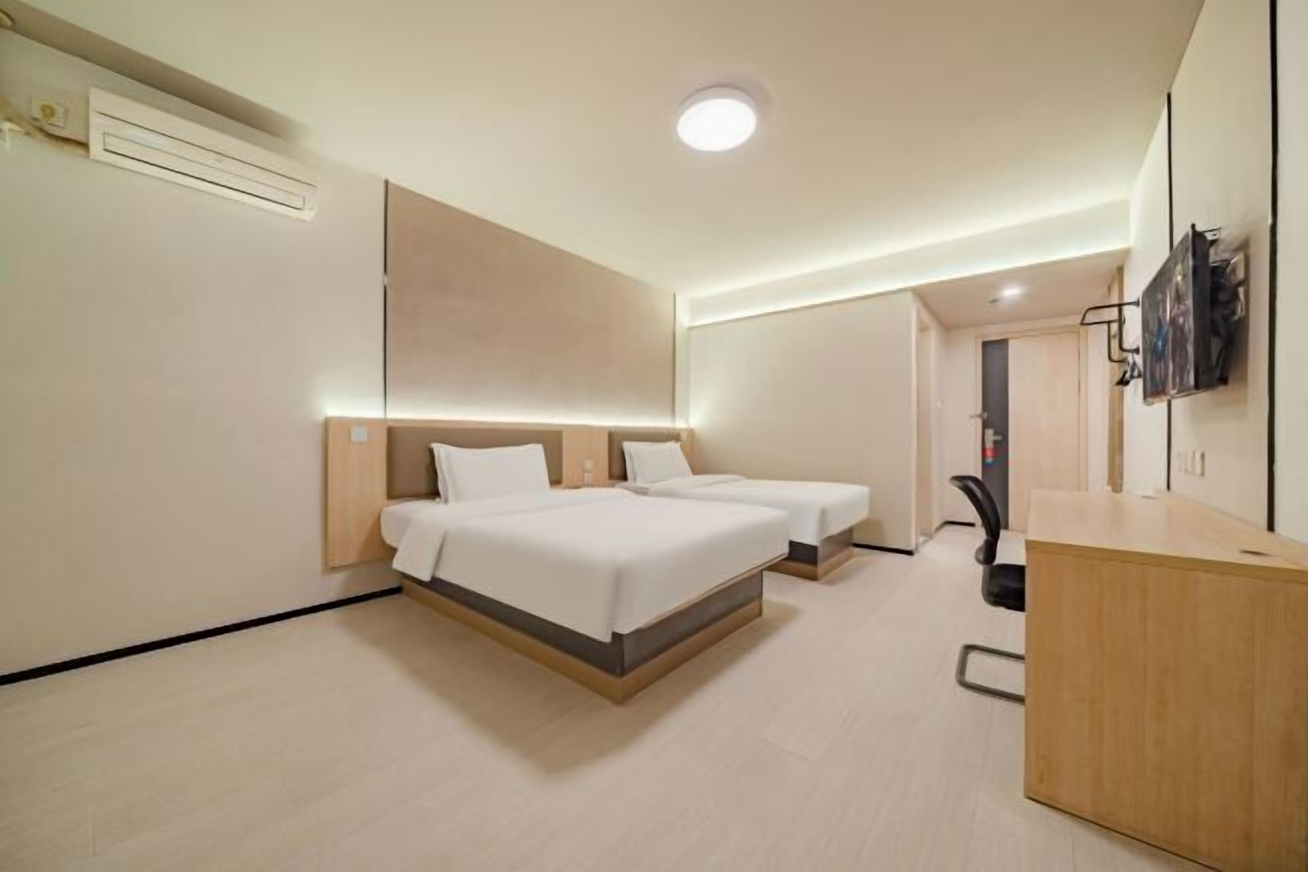 Ein Hotelzimmer mit zwei Betten, einem Schreibtisch und einem Stuhl.