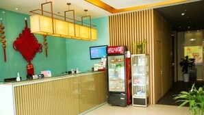 A reception area with a modern design, including a reception desk, a digital screen, a refrigerator, and a wall-mounted decorative piece. - Boinn Zhi Xuan Hotel（Nantong Tongzhou Coach Station Jianshe Lu ） (Nantong)