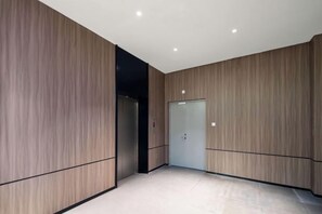 A modern interior with wooden panel walls, a tiled floor, and a door. - Boinn Zhi Xuan Hotel（Nantong Tongzhou Coach Station Jianshe Lu ） (Nantong)