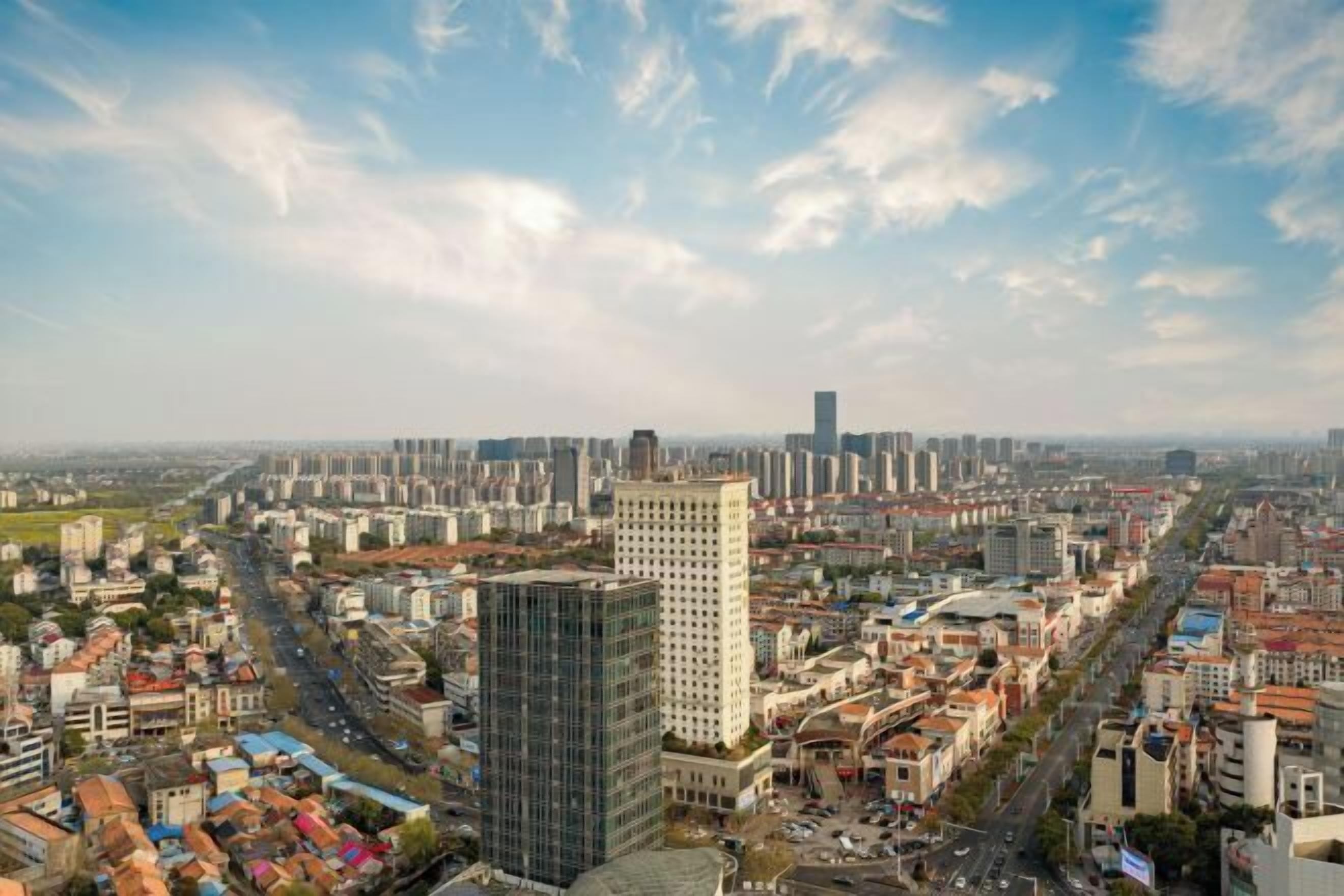 A cityscape with modern buildings, a prominent skyscraper, and a mix of residential and commercial structures.