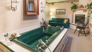A bathroom with a large green bathtub, a wooden-framed mirror, and a green sofa in the adjacent living area. - The Globe Inn (East Greenville)