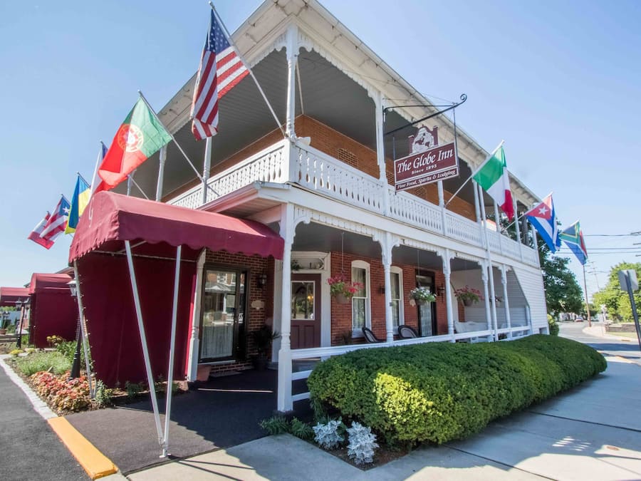 Un edificio de dos pisos con balcón, banderas y un cartel que dice 'The Globe Inn'.