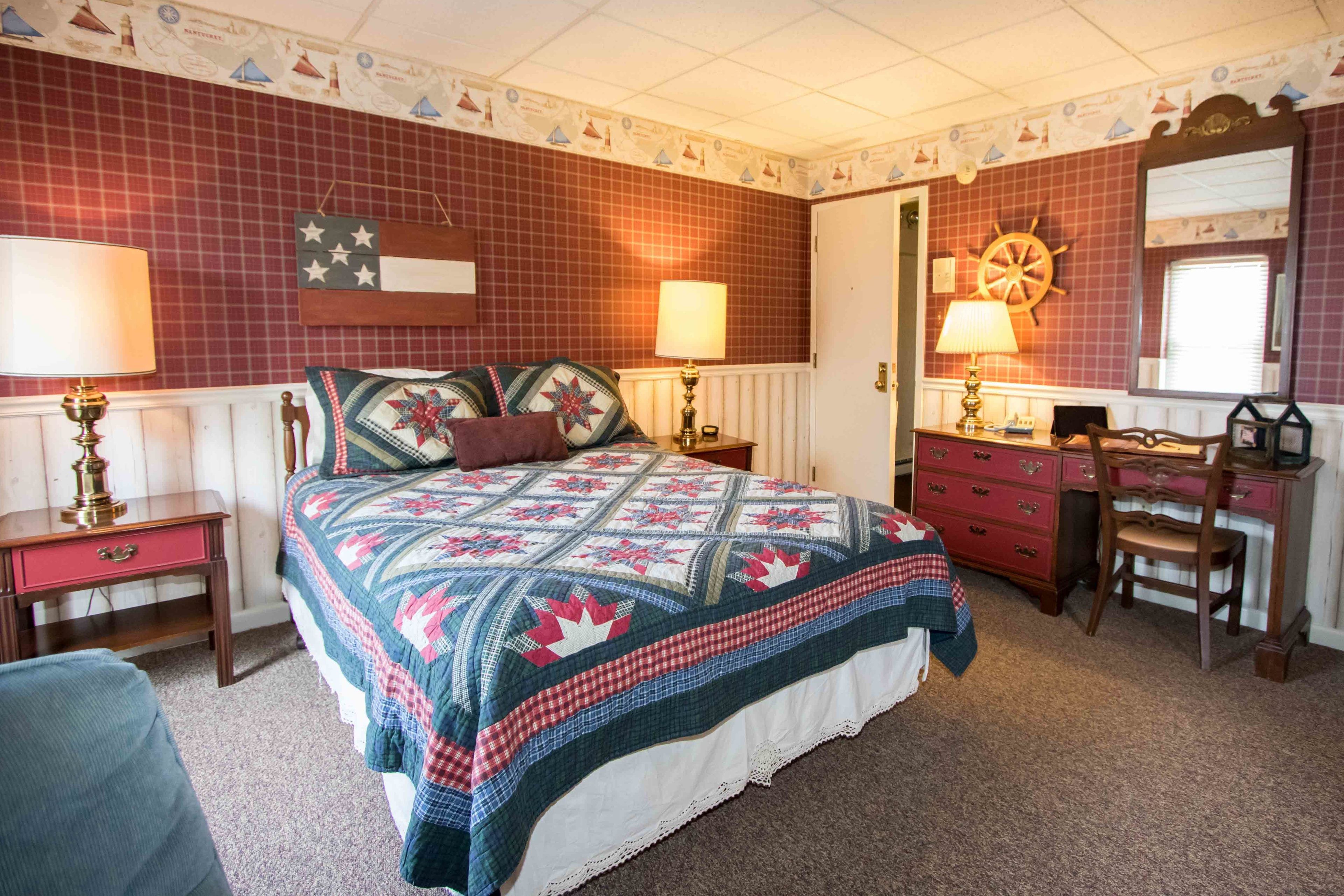 A bedroom with a bed, dresser, chair, and two lamps.