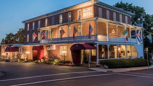 A historic hotel with a prominent sign, multiple flags, and a balcony. - The Globe Inn (East Greenville)
