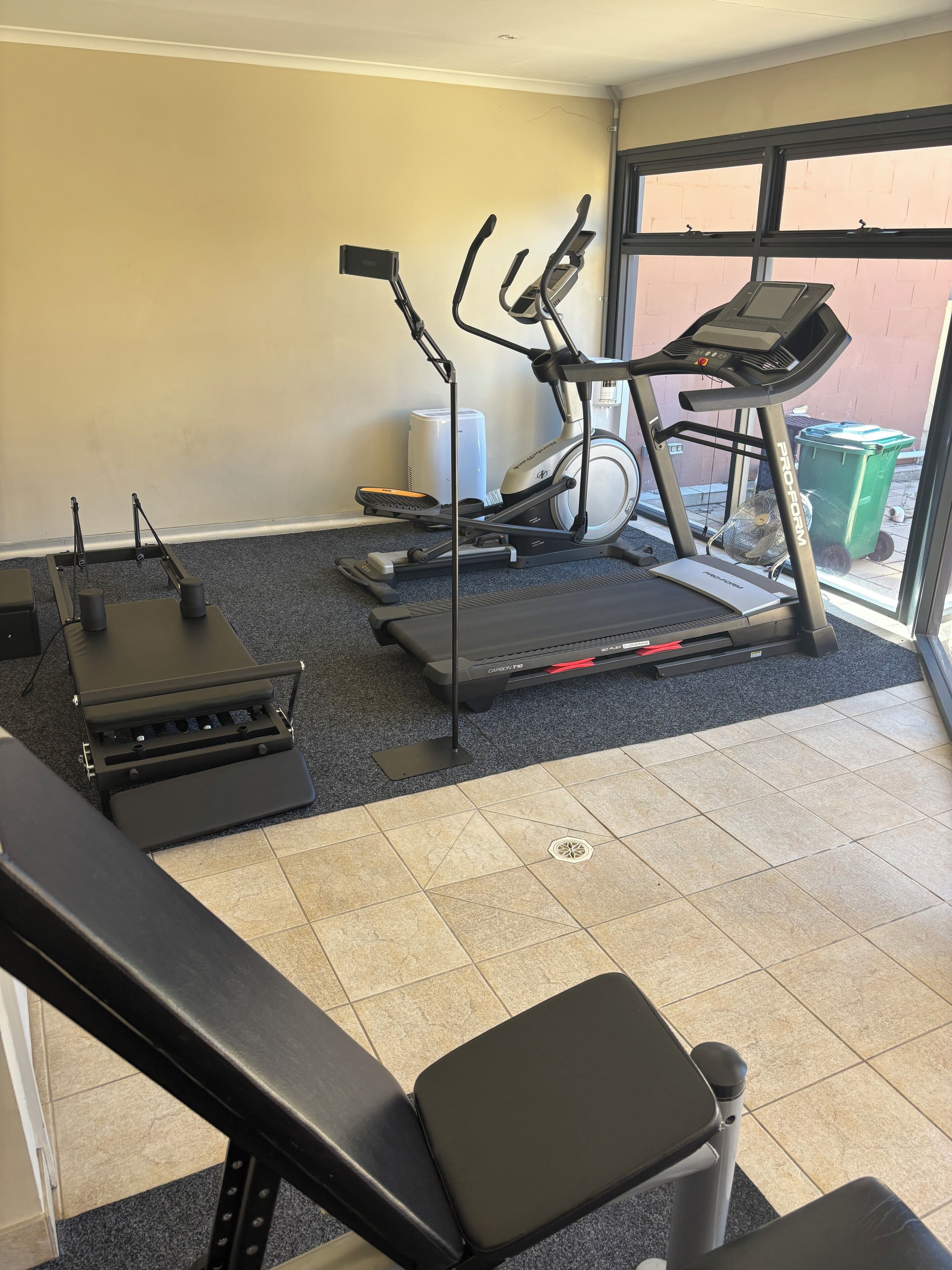 Ein Fitnessraum mit Trainingsgeräten, darunter Laufbänder, ein Ergometer und ein Rudergerät.