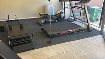 Ein Fitnessraum mit Trainingsgeräten, darunter Laufbänder, ein Ergometer und ein Rudergerät.