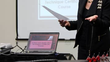 Una persona presentando en un seminario con un portátil que muestra 'Curso de Certificación de Color y Técnica de Aplicación'.
