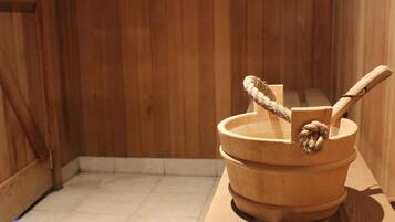 Una sauna de madera con un banco de madera y un cubo de madera con asa de cuerda.