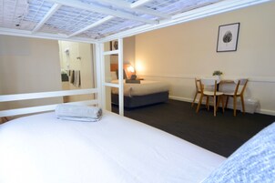 Un dormitorio con una cama, un escritorio y una silla. Hay un espejo, una lámpara y un cuadro en la pared.