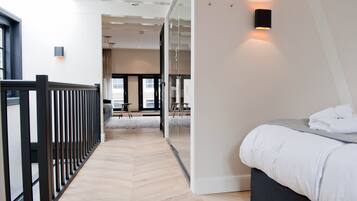 Ein modernes Hotelzimmer mit Bett, Glastrennwand und Blick auf die Stadt.