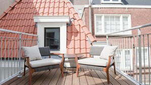 Una terraza de madera con dos sillas blancas acolchadas y una pequeña mesa redonda.