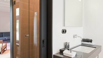 Un baño moderno con mampara de vidrio, un espejo grande y un lavabo con toalla.