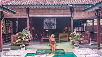 Relax by the pool surrounded by lush greenery and traditional architecture.
