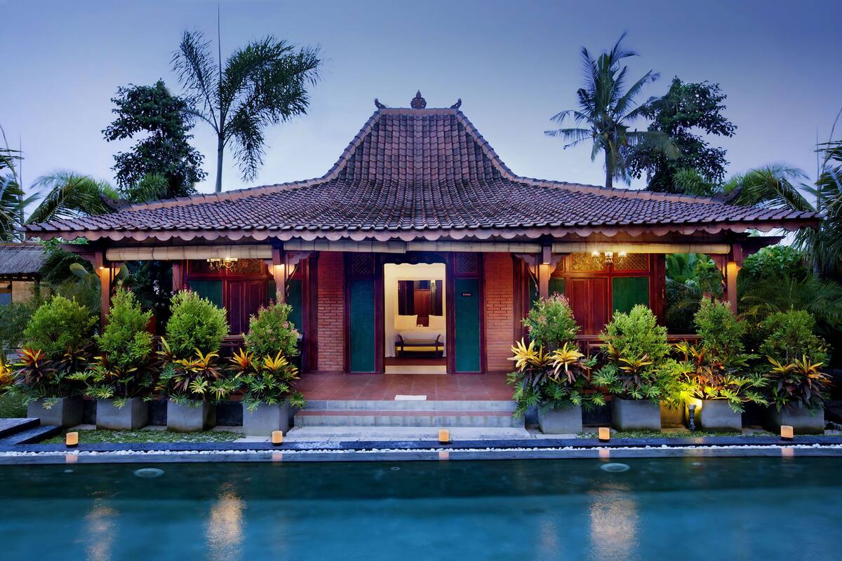 A traditional building with a tiled roof, a front entrance, and a pool in front.