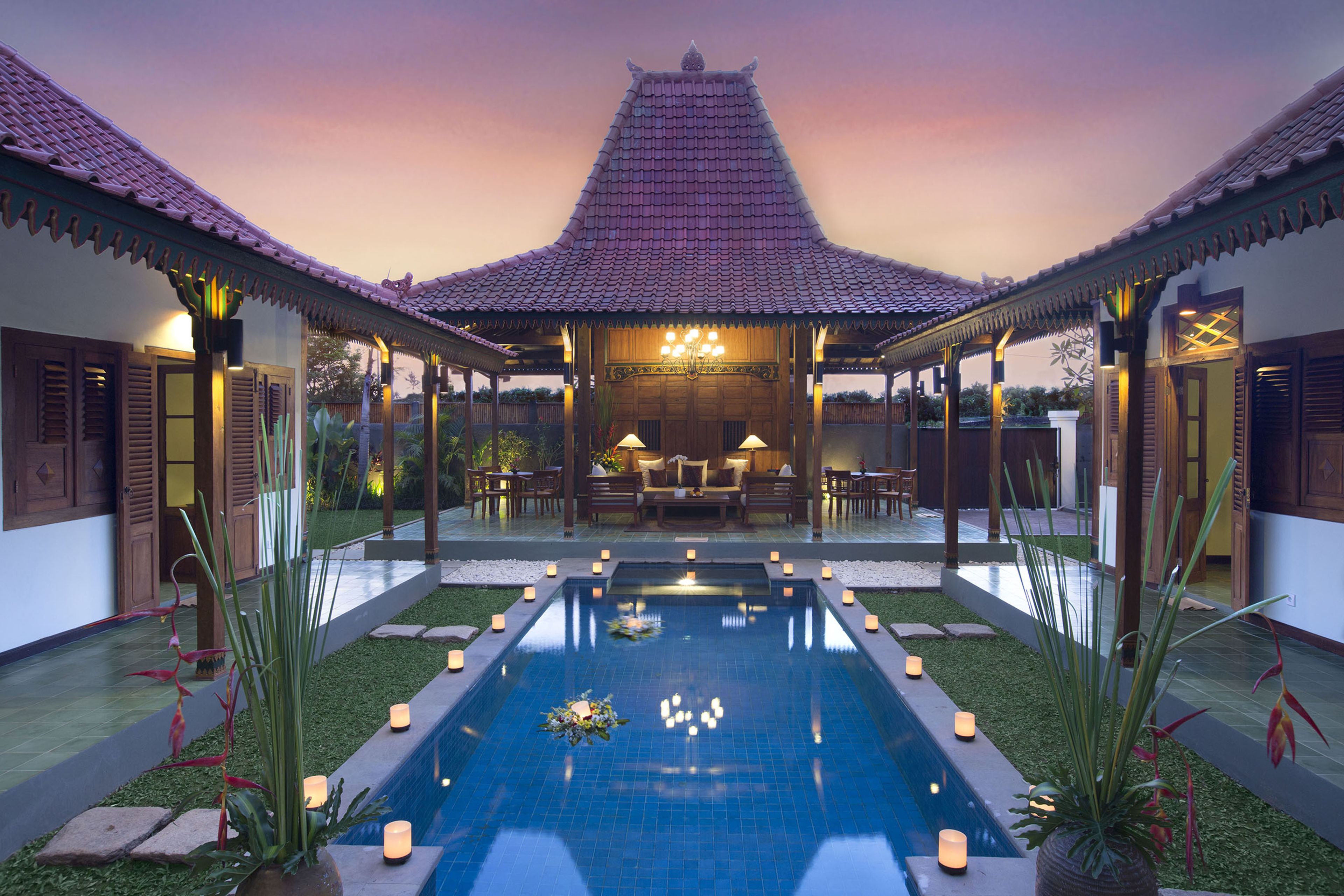 Ein Pool im traditionellen Stil mit einem gefliesenen Dach, umgeben von einer Terrasse mit Sitzgelegenheiten und Kerzen.
