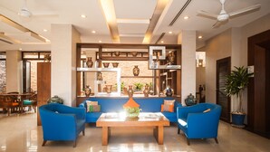 A modern living room with blue sofas, a wooden coffee table, and decorative vases on shelves. - Crystal Inn Phuket (Phuket)