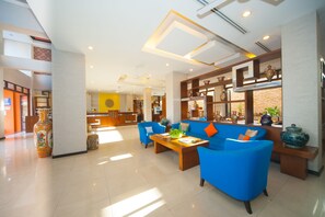 Relax in our spacious lobby, featuring a central seating area with sofas and a coffee table, alongside a reception desk and kitchen area.