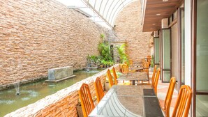 A restaurant with a brick wall, a small water feature, and wooden chairs and tables. - Crystal Inn Phuket (Phuket)