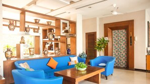 A modern living room with blue sofas, a wooden coffee table, and decorative vases on shelves. - Crystal Inn Phuket (Phuket)