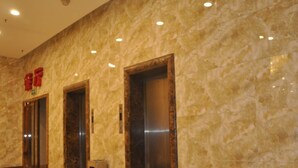 A marble wall with three elevator doors and a trash bin. - GreenTree Inn TaiYuan Jiancaoping District XingHua Street Hotel (Taiyuan)