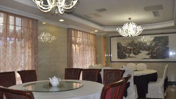 A dining area with a round glass table, chairs, and a chandelier.