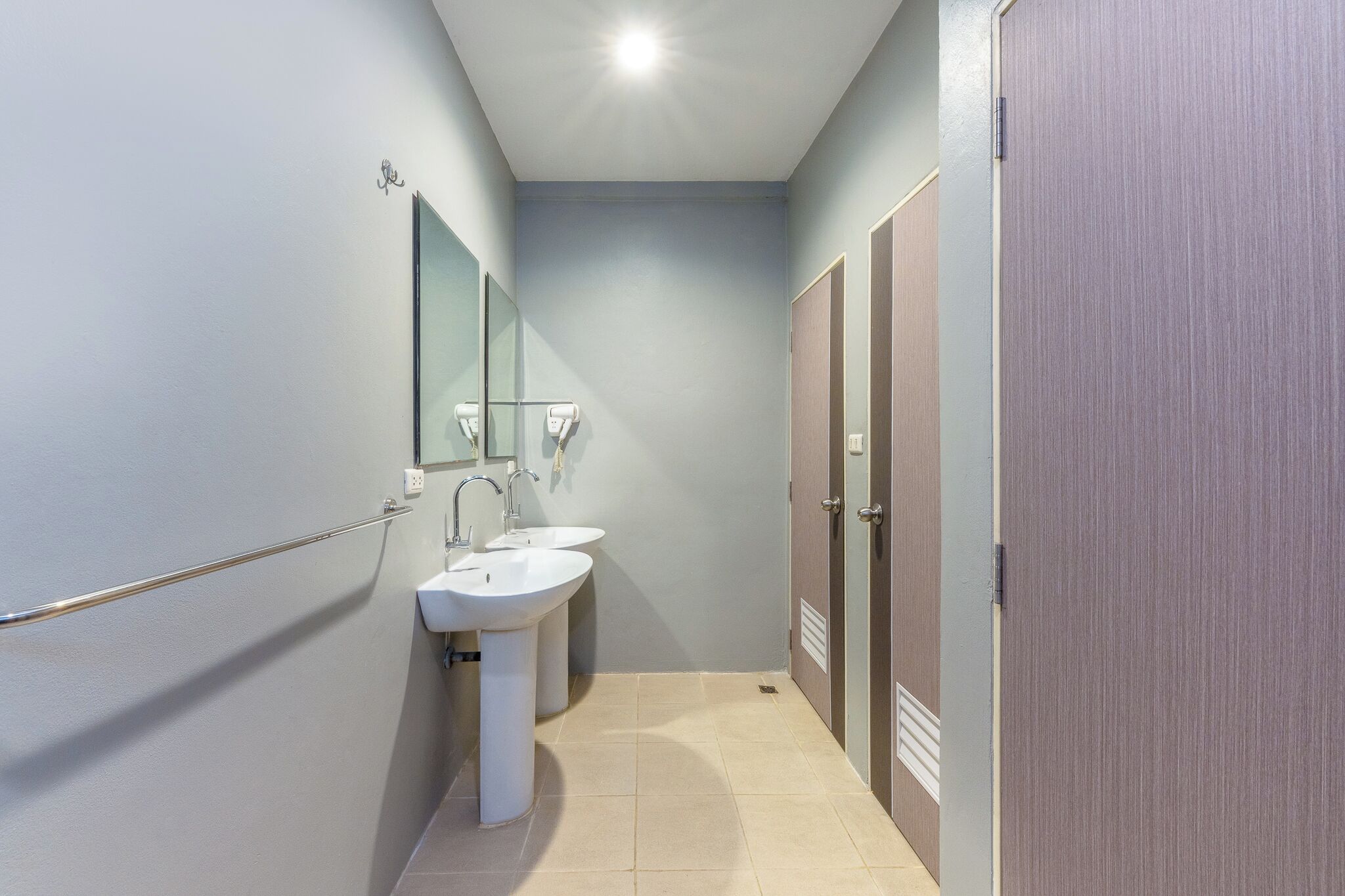 A narrow bathroom with two sinks, a mirror, and a door.